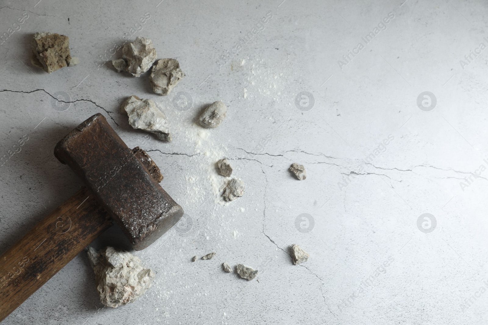 Photo of One sledgehammer and broken stones on grey textured background, flat lay. Space for text