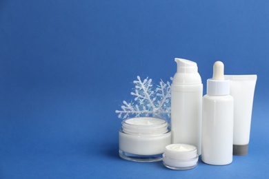 Beautiful composition with cosmetic products on blue background, space for text. Winter care