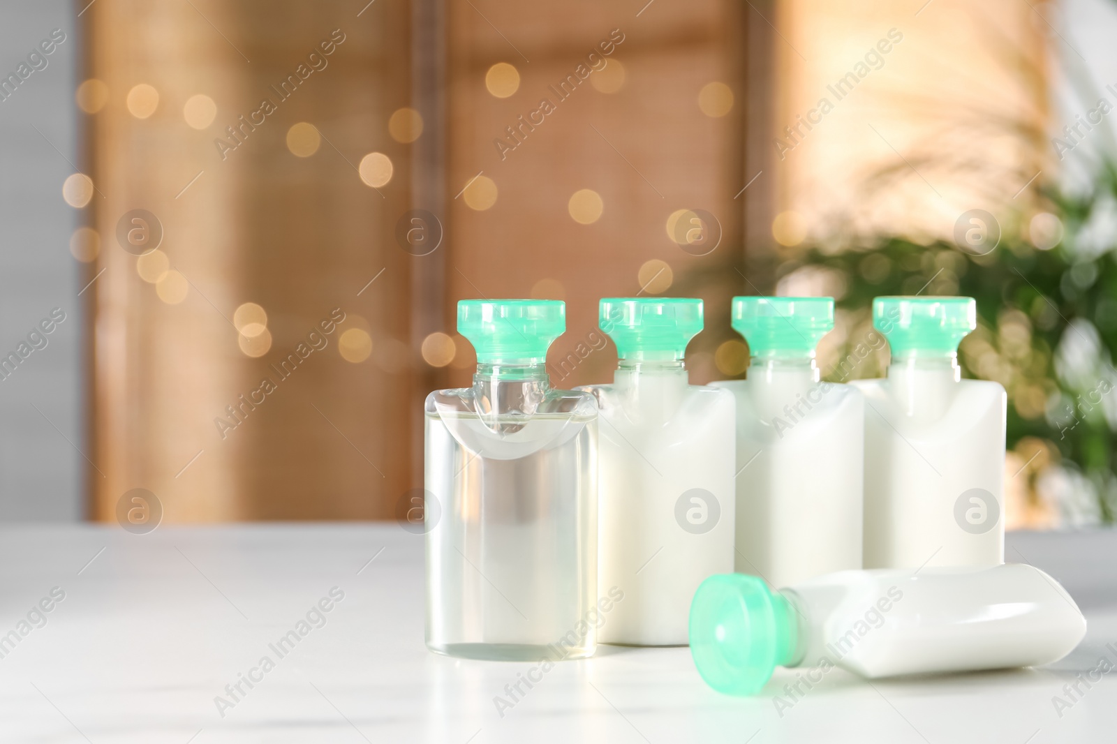 Photo of Mini bottles of cosmetic products on white table against blurred background. Space for text