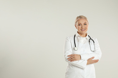 Photo of Portrait of mature doctor with stethoscope on light grey background. Space for text