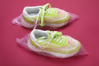 Photo of Sneakers in shoe covers on pink background, closeup