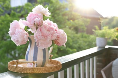 Beautiful pink peony flowers in vase on balcony railing outdoors