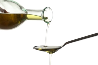 Photo of Pouring fresh olive oil into spoon on white background