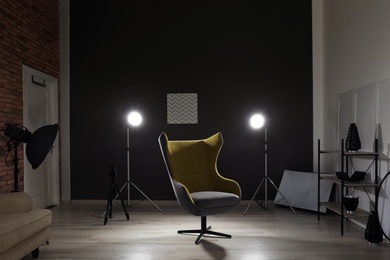 Interior of modern photo studio with armchair and professional equipment