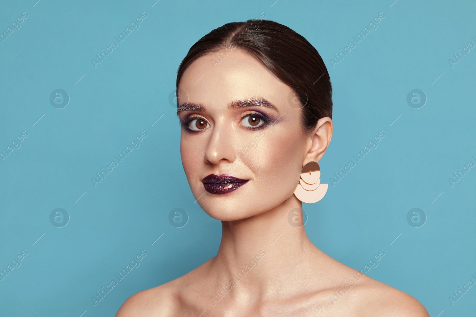 Photo of Beautiful young woman with glitter makeup on blue background