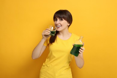 Photo of Young woman using mouthwash on yellow background