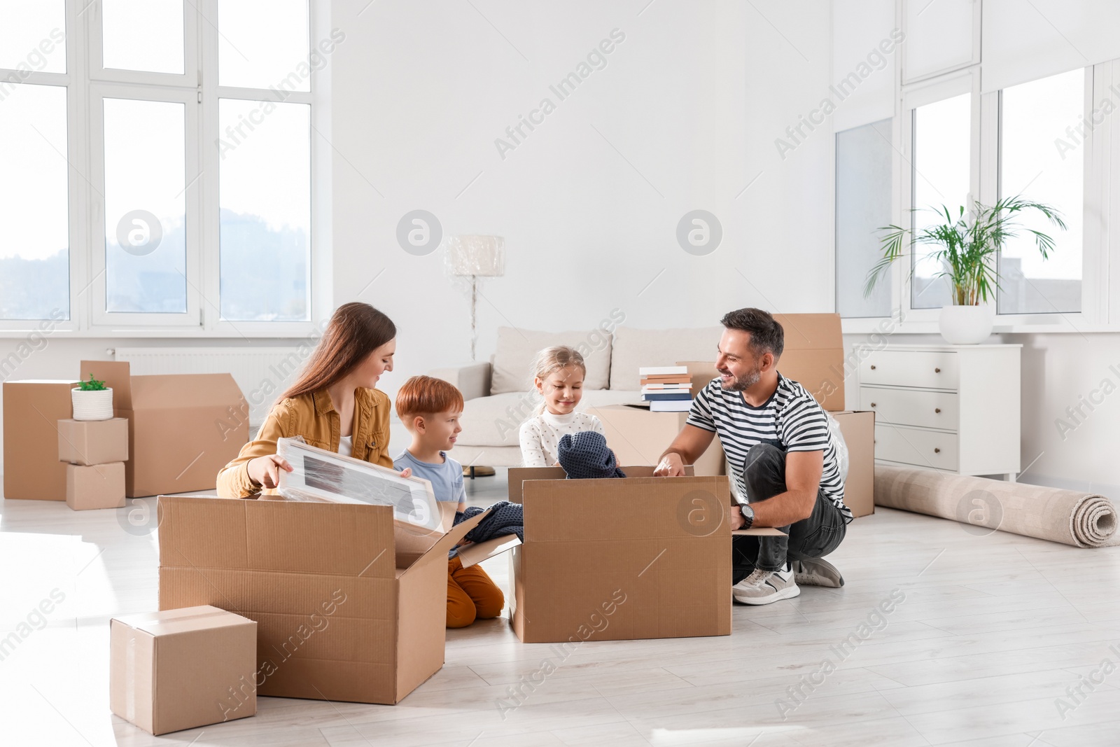 Photo of Happy family unpacking boxes in new apartment. Moving day