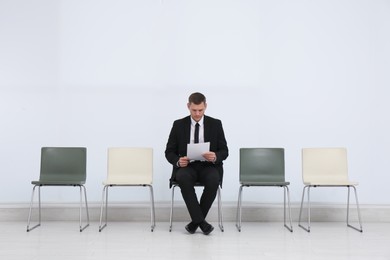 Photo of Man with papers waiting for job interview in office hall