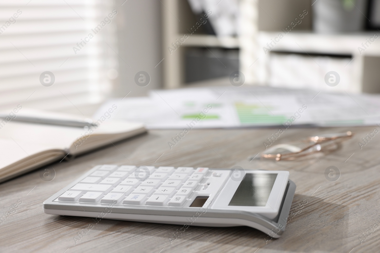 Photo of One calculator on light wooden table in office, closeup