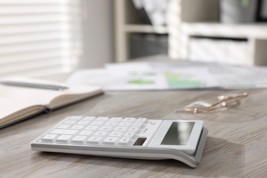 Photo of One calculator on light wooden table in office, closeup