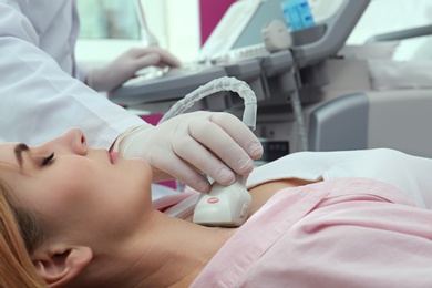 Doctor conducting ultrasound examination of thyroid gland in clinic