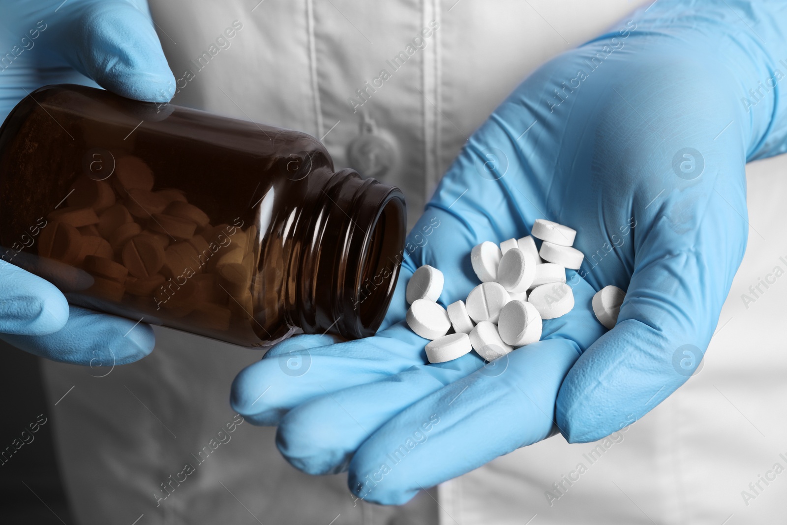 Photo of Doctor pouring pills from bottle onto hand, closeup view