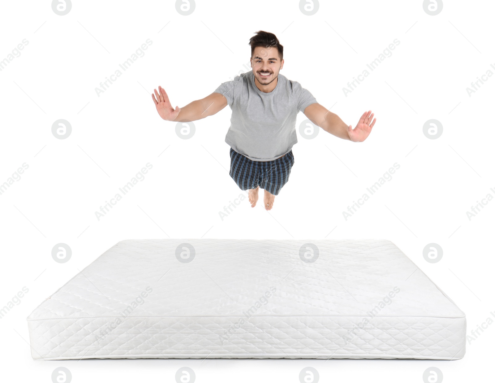 Photo of Young man jumping on mattress against white background