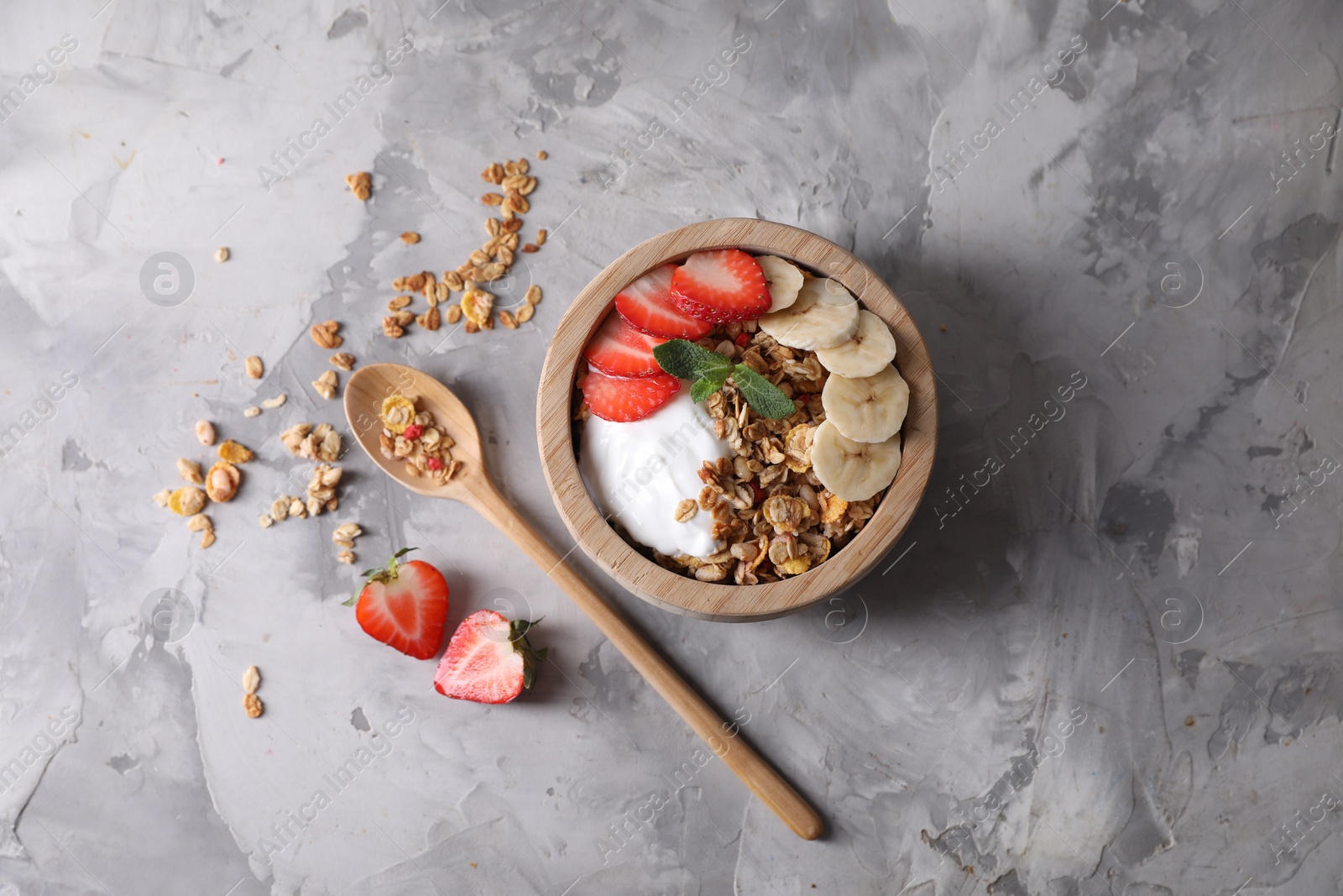 Photo of Tasty granola served on gray textured table, flat lay