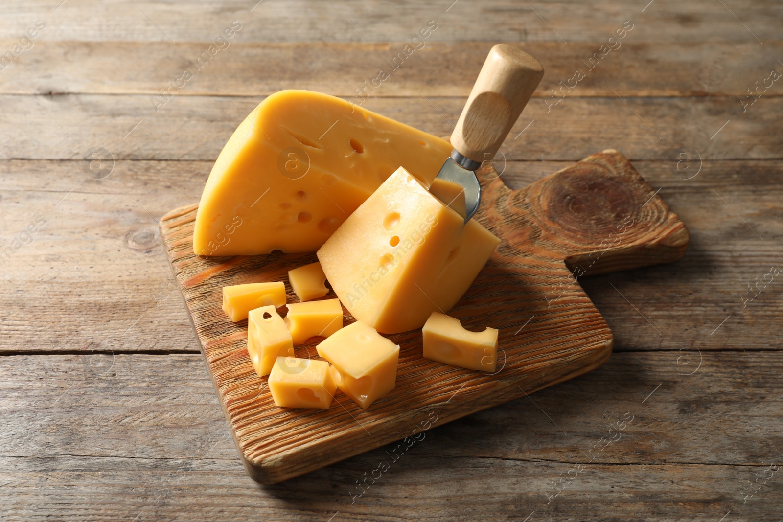 Photo of Serving board with delicious cheese on wooden table