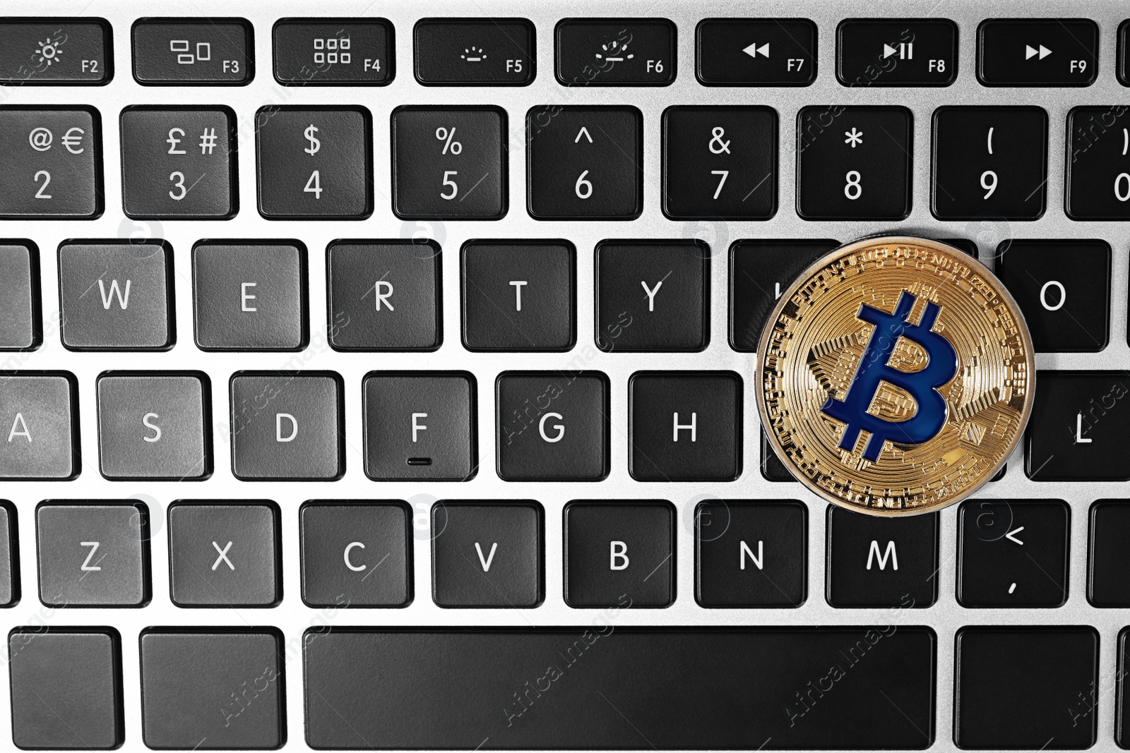 Photo of Golden bitcoin on computer keyboard, top view. Space for text