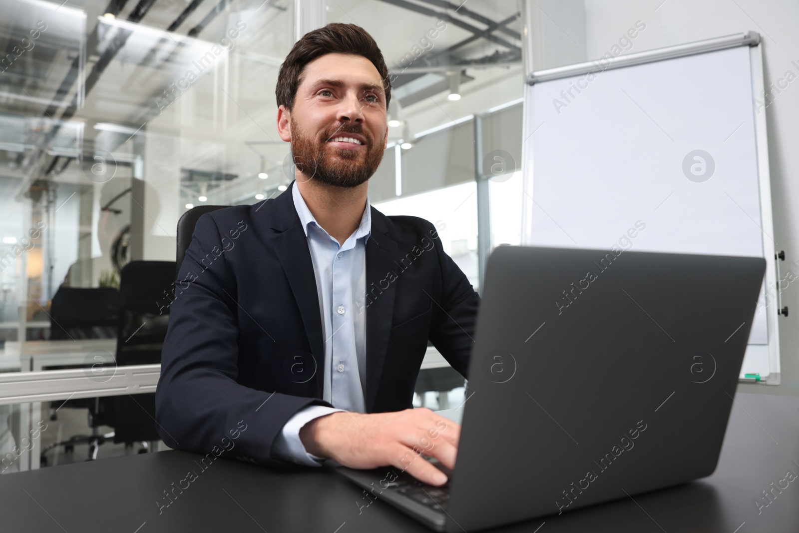 Photo of Man working on laptop at black desk in office