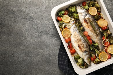 Photo of Delicious fish with vegetables and lemon in baking dish on grey textured table, top view. Space for text