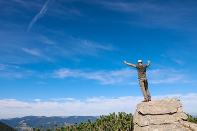 Photo of Man enjoying picturesque view on cliff in mountains. Space for text
