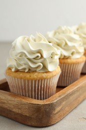 Photo of Tasty cupcakes with vanilla cream on light grey table, closeup