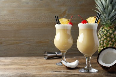 Tasty Pina Colada cocktail and ingredients on wooden table