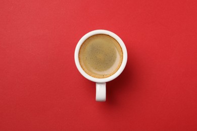 Photo of Aromatic coffee in cup on red background, top view