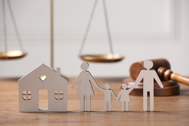 Photo of Family law. Figure of parents with children, house model, scales, gavel on wooden table, space for text