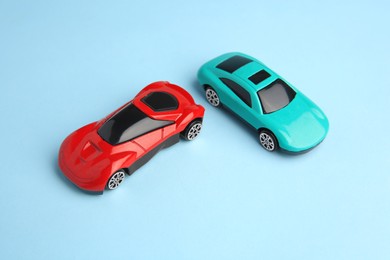 Two bright cars on light blue background, above view. Children`s toys