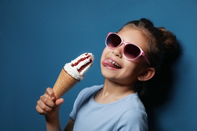 Photo of Adorable little girl with delicious ice cream against color background