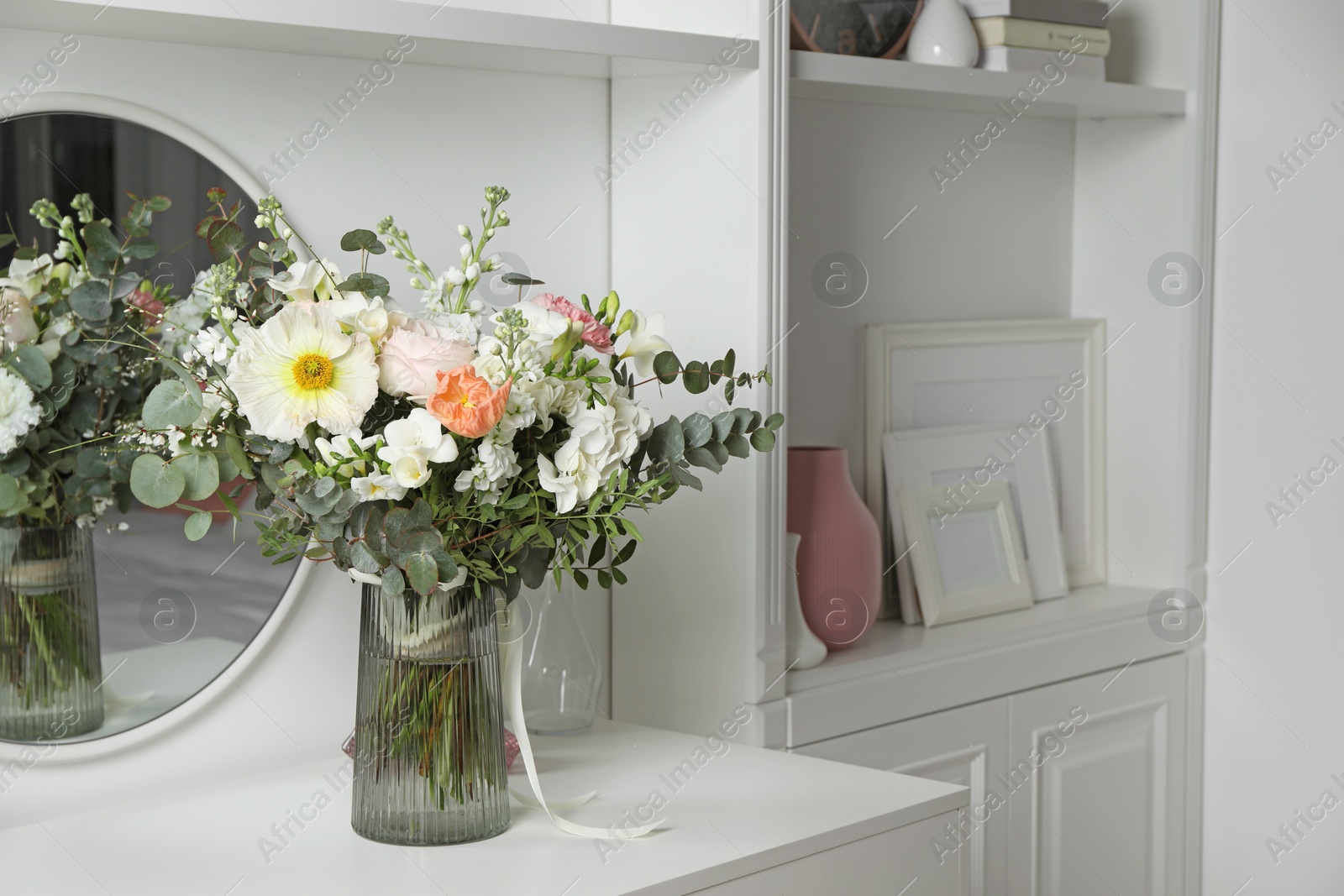 Photo of Bouquet of beautiful flowers on white table near mirror indoors. Space for text