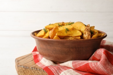 Photo of Bowl of delicious oven baked potatoes with dill on table