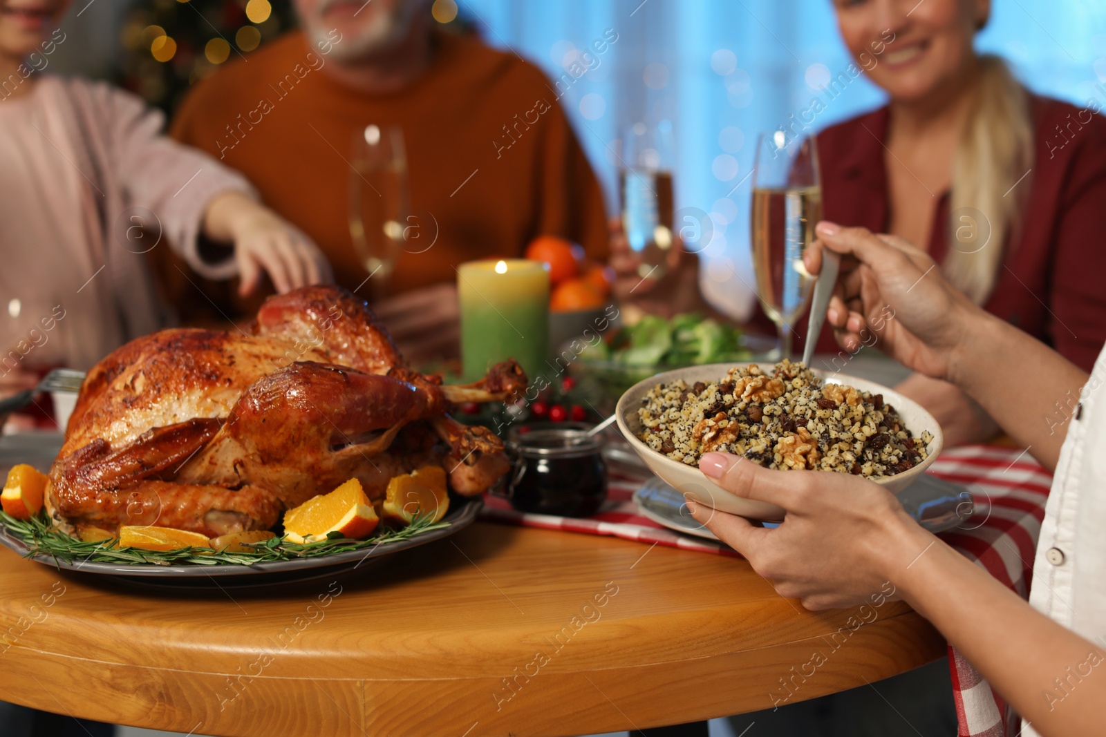 Photo of Woman with bowl of traditional Christmas Slavic dish kutia and her family at festive dinner