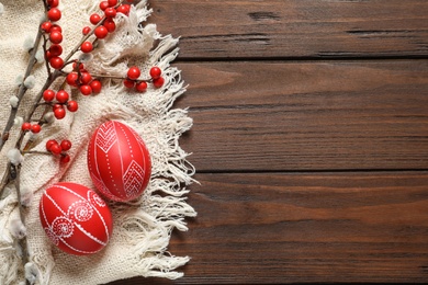 Flat lay composition with painted red Easter eggs on wooden table, space for text