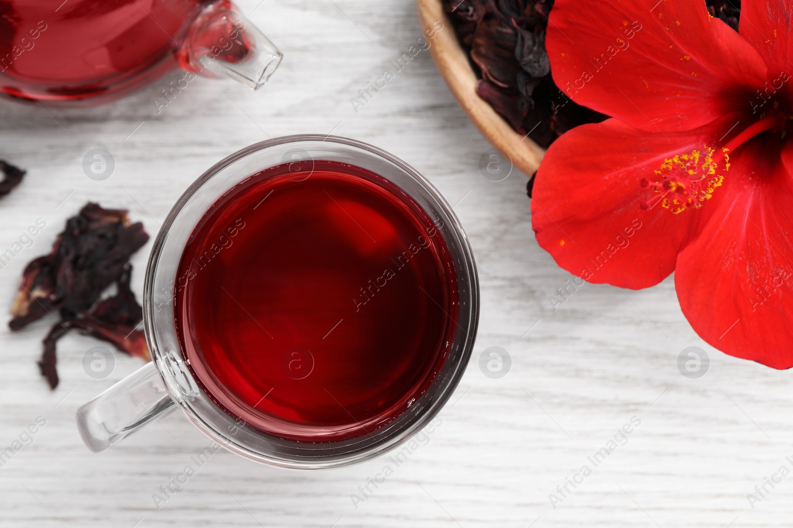 Photo of Delicious hibiscus tea and flowers on white wooden table, flat lay