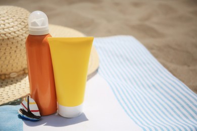 Sunscreens and beach accessories on sand, space for text. Sun protection care