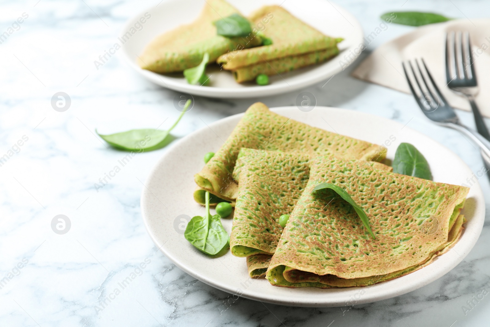 Photo of Tasty spinach crepes on white marble table