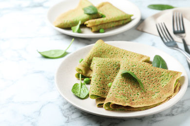 Photo of Tasty spinach crepes on white marble table