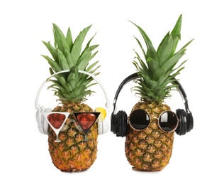 Funny pineapples with headphones and sunglasses on white background