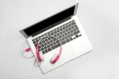 Modern headphones and laptop on white background, top view