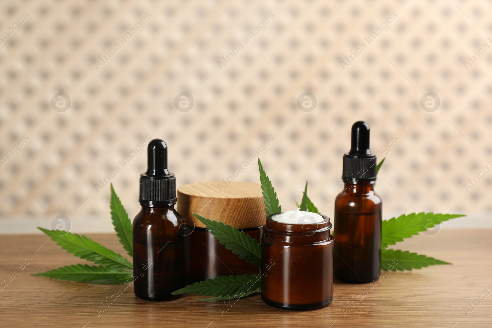 Photo of Cream, hemp leaves, bottles of CBD oil and THC tincture on wooden table