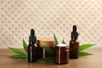 Photo of Cream, hemp leaves, bottles of CBD oil and THC tincture on wooden table
