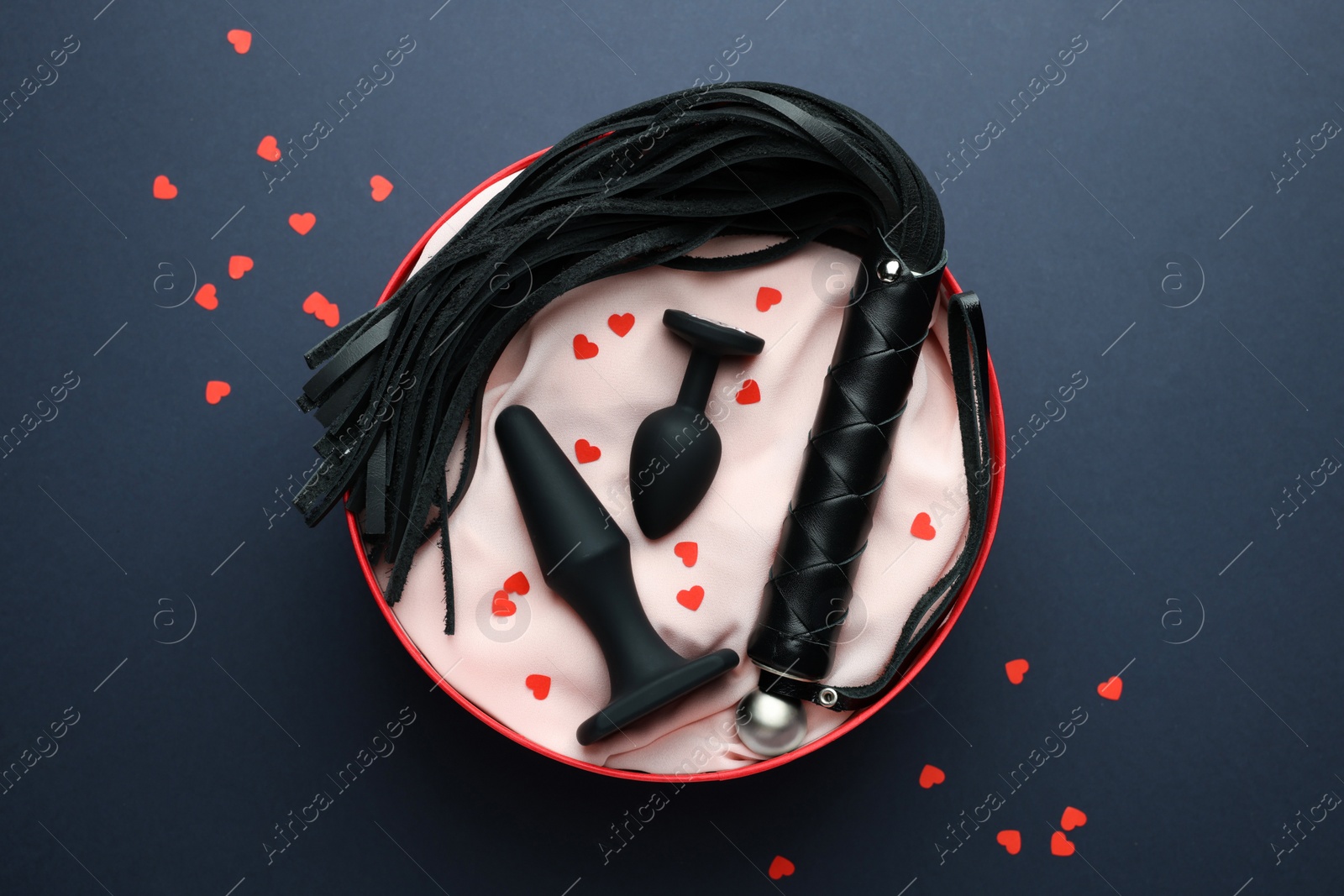 Photo of Gift box with different sex toy on dark blue background, flat lay