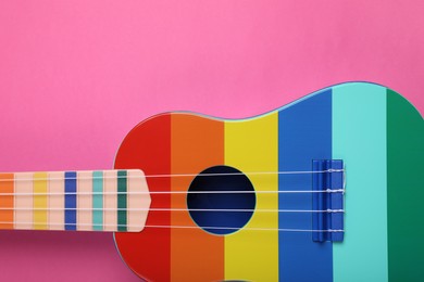 Colorful ukulele on pink background, top view. String musical instrument