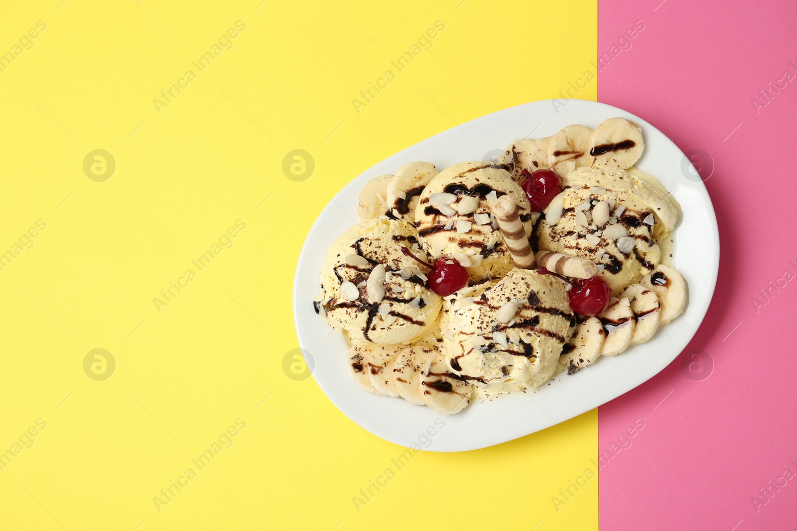 Photo of Delicious dessert with banana ice cream on color background, top view. Space for text