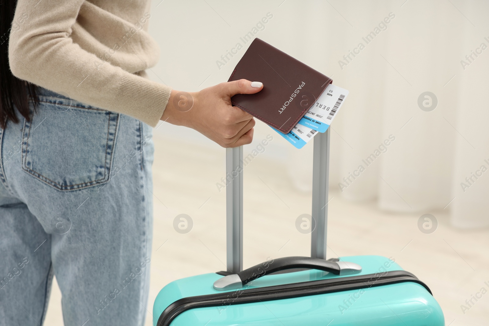 Photo of Woman with suitcase, passport and tickets on blurred background, closeup
