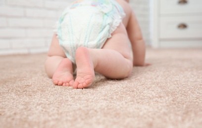 Photo of Cute little baby crawling on carpet indoors, closeup