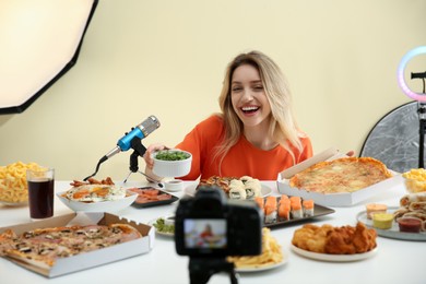 Photo of Food blogger recording eating show on camera against light background. Mukbang vlog