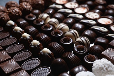 Photo of Many different delicious chocolate candies as background, closeup view