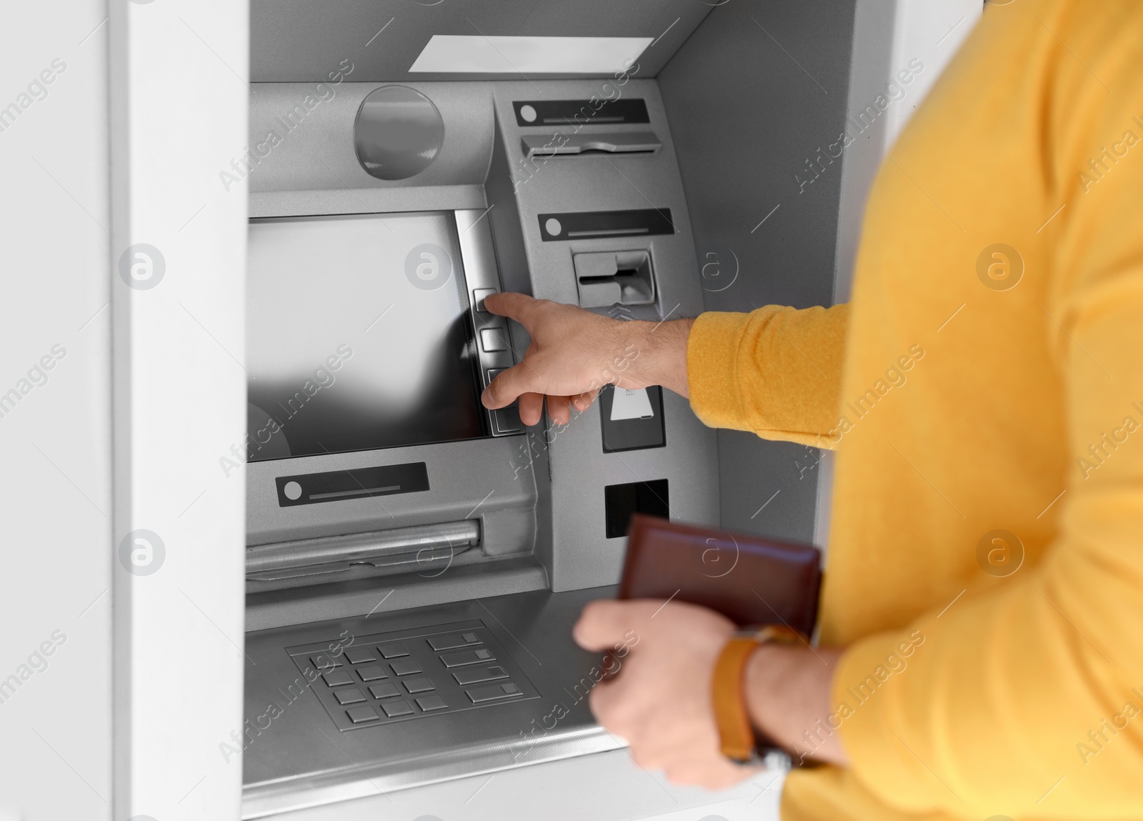 Photo of Young man using modern cash machine outdoors, closeup