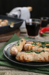 Tasty fresh grilled sausages with sauce on wooden table, closeup